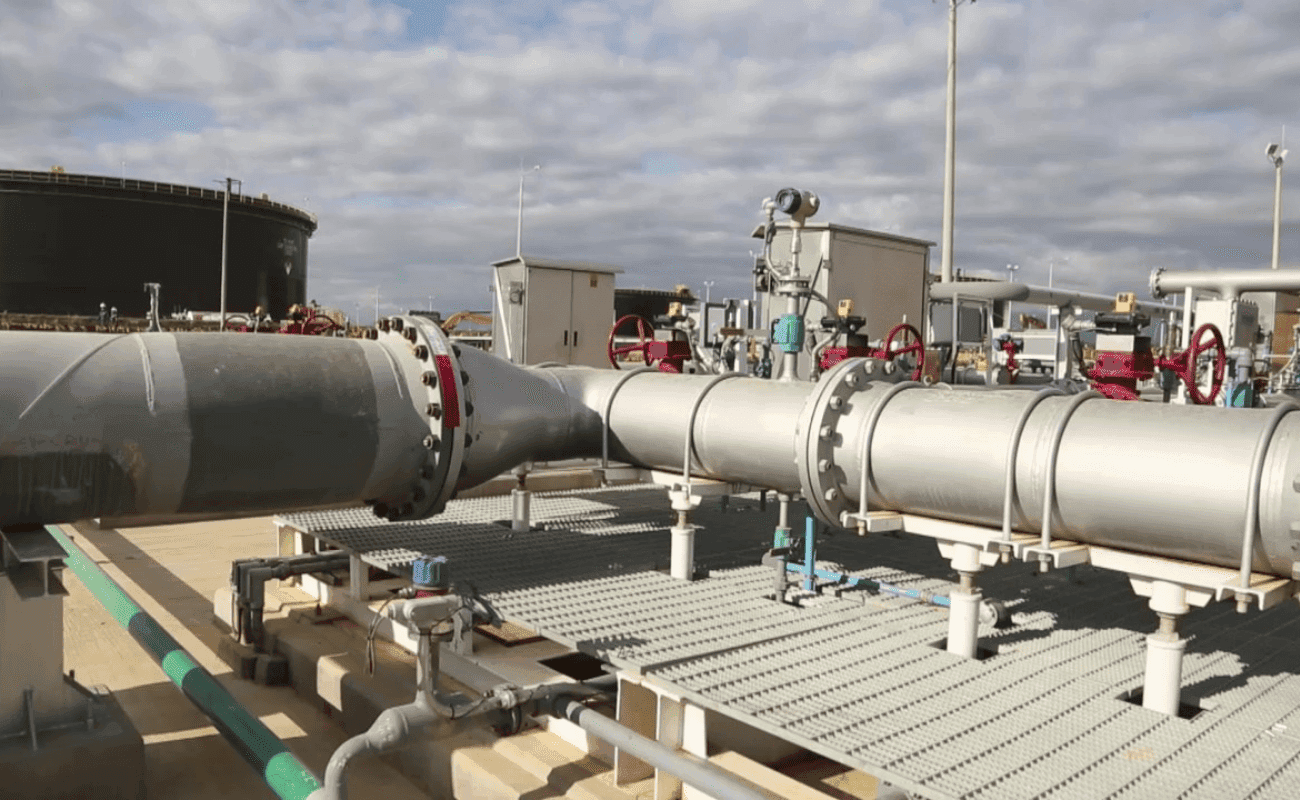 Línea de tubería y válvulas de un sistema de bombeo junto a un tanque de almacenamiento