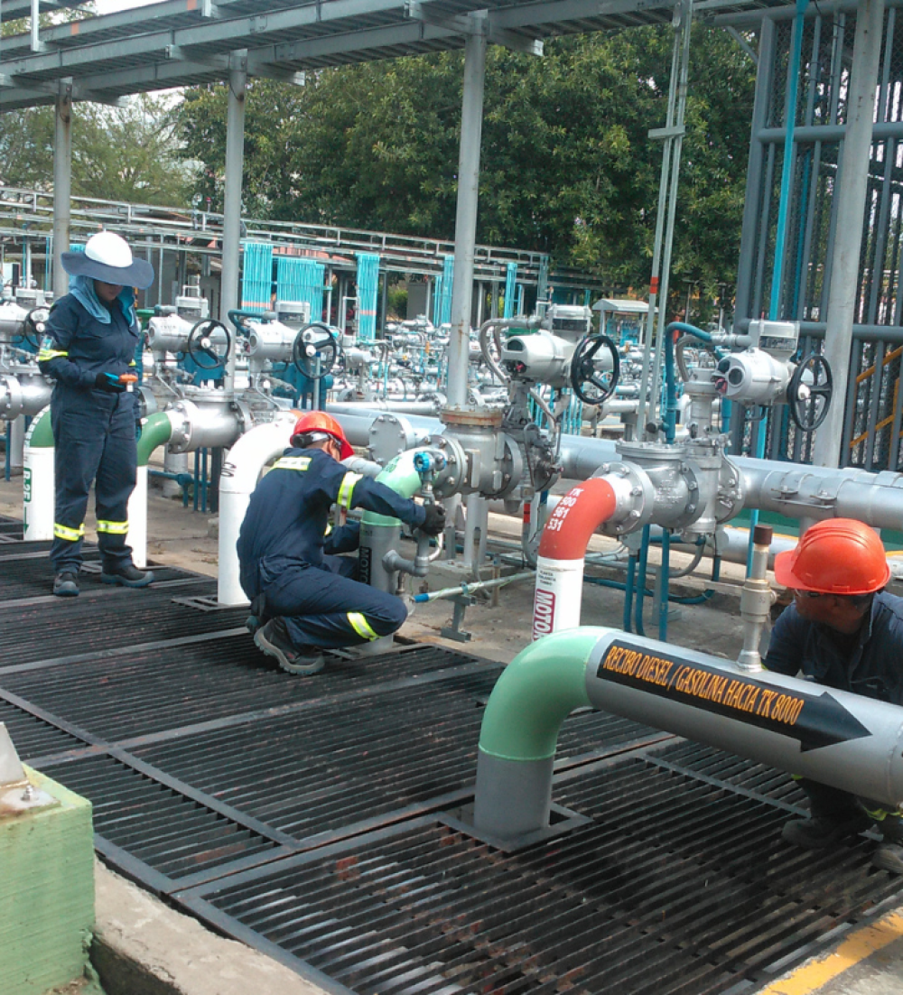 OBS personnel working on a pipe and valve manifold at a station