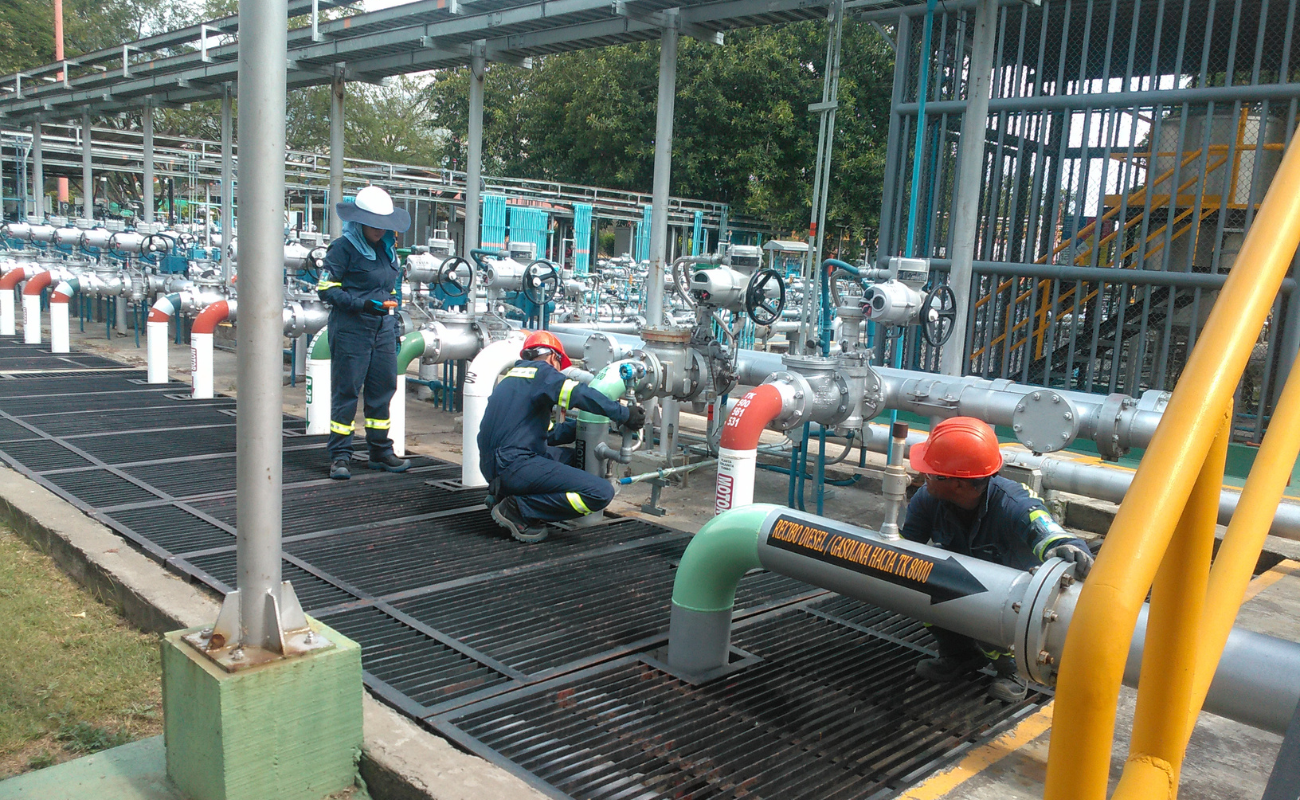 OBS personnel working on a pipe and valve manifold at a station